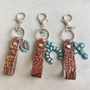Tooled leather keychains with turquoise and red stone charms, western style accessories.