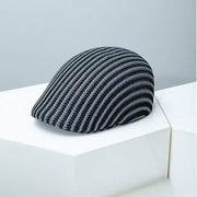 Textured striped flat cap in black and white with a breathable knit design.
