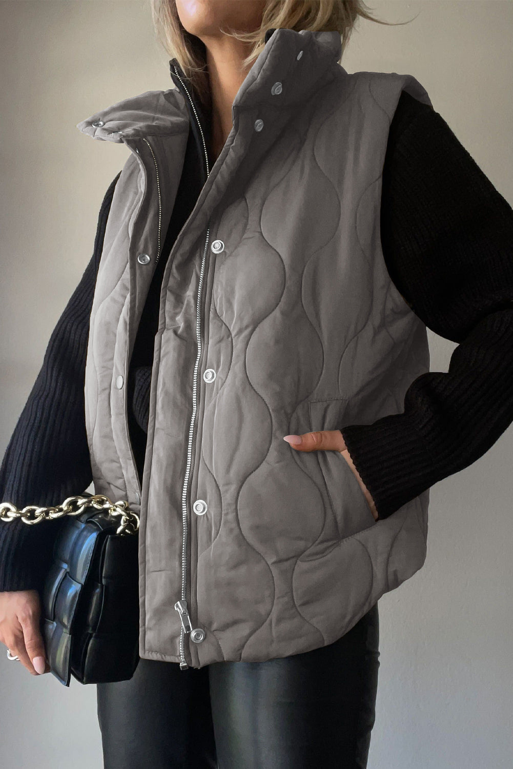 Quilted stand-collar gilet in charcoal with a zip and snap front, and side pockets.