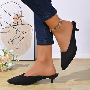 Black pointed-toe kitten heel mules with a low heel and open back.