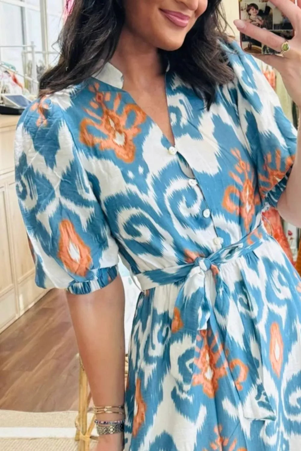 Ikat floral midi dress with puff sleeves, V-neck, button front, and tie waist in blue, white, and orange cotton.