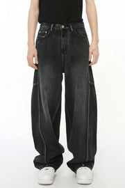Dark wash denim trousers with exaggerated seam details and a wide leg