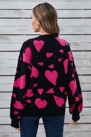 Black intarsia knit jumper with allover pink hearts pattern, crew neck, long sleeves.