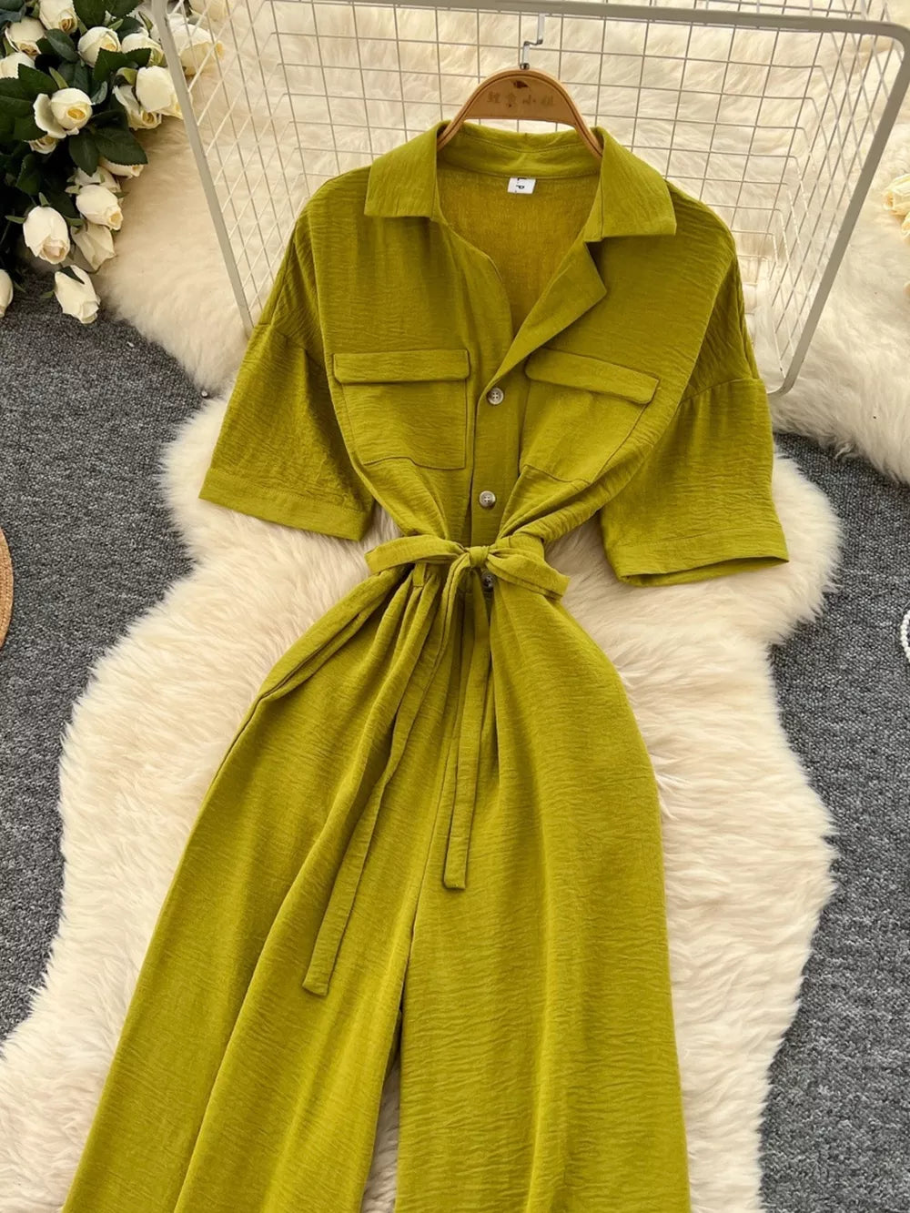 Belted wide-leg jumpsuit in green with short sleeves, button front, and chest pockets.