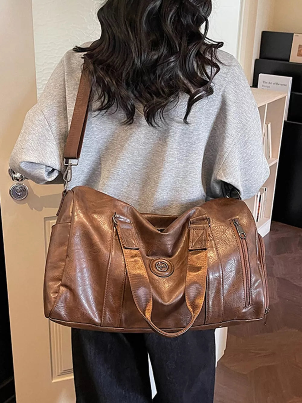 Brown pu leather duffel bag with zippered pockets and top handles.