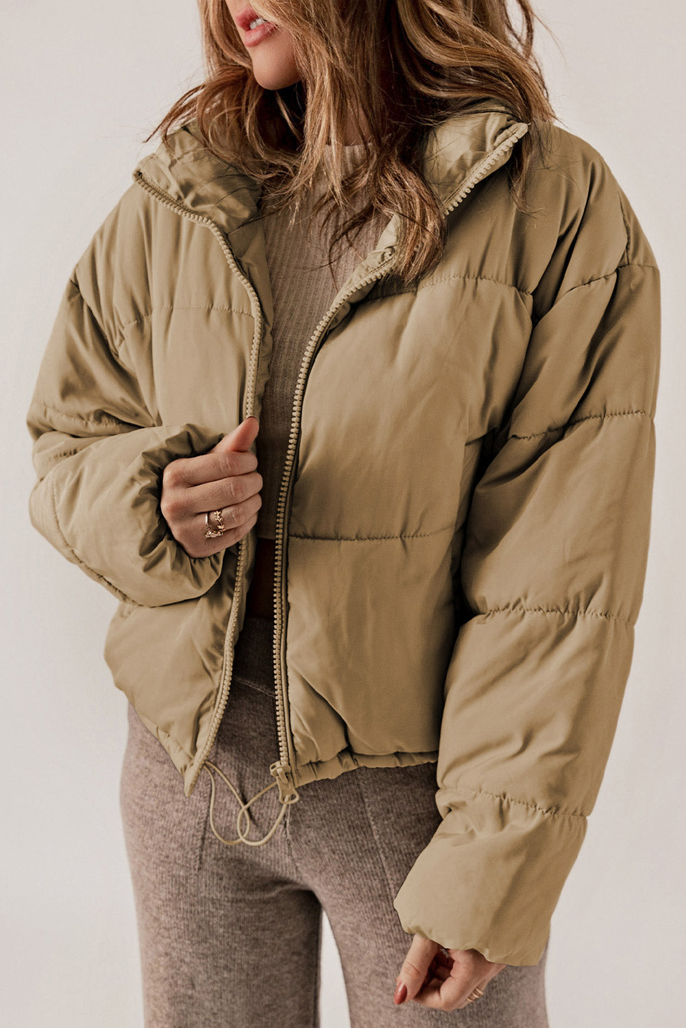 Taupe cropped puffer jacket with hooded collar and zipper closure.