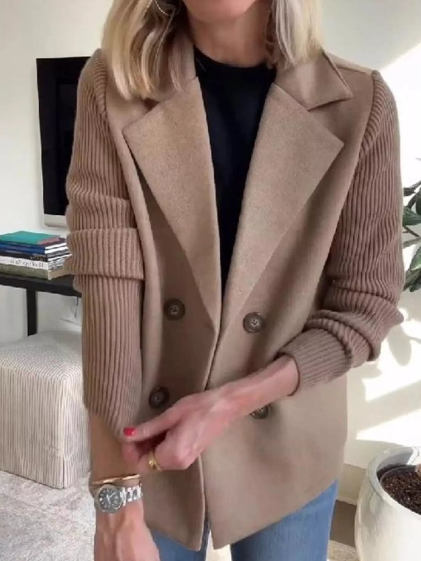 Tan double-breasted trench coat with knit sleeves and notched lapels.