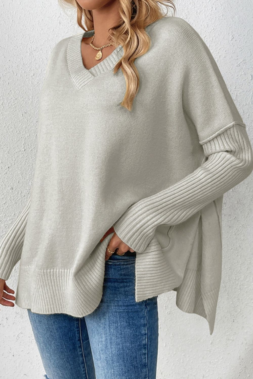 Gray v-neck knit sweater with asymmetric hemline and ribbed sleeves.