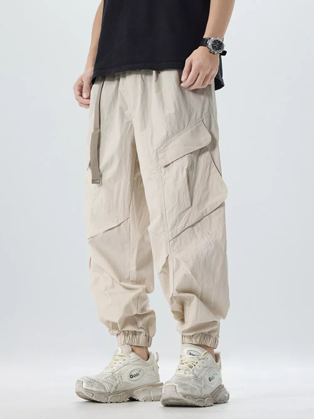 Oversized khaki cargo pants with adjustable belt and multiple pockets.