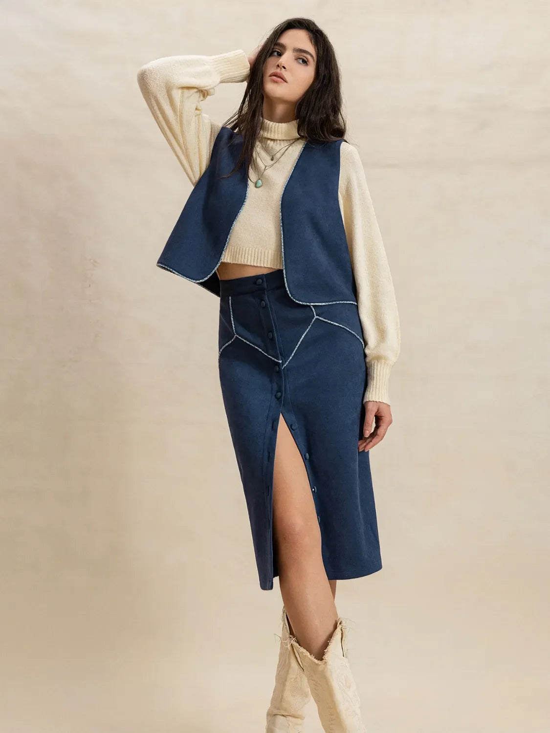 Peacock blue suede vest and button-front skirt set with contrast stitching and a high slit.