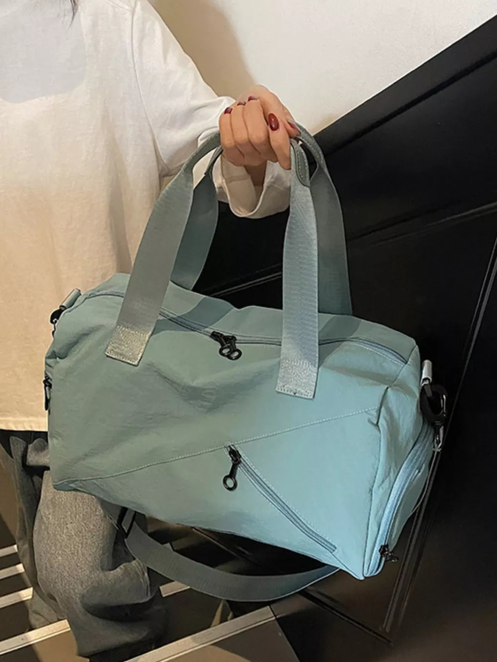 Light blue nylon duffel bag with multiple zippered pockets and grey straps.