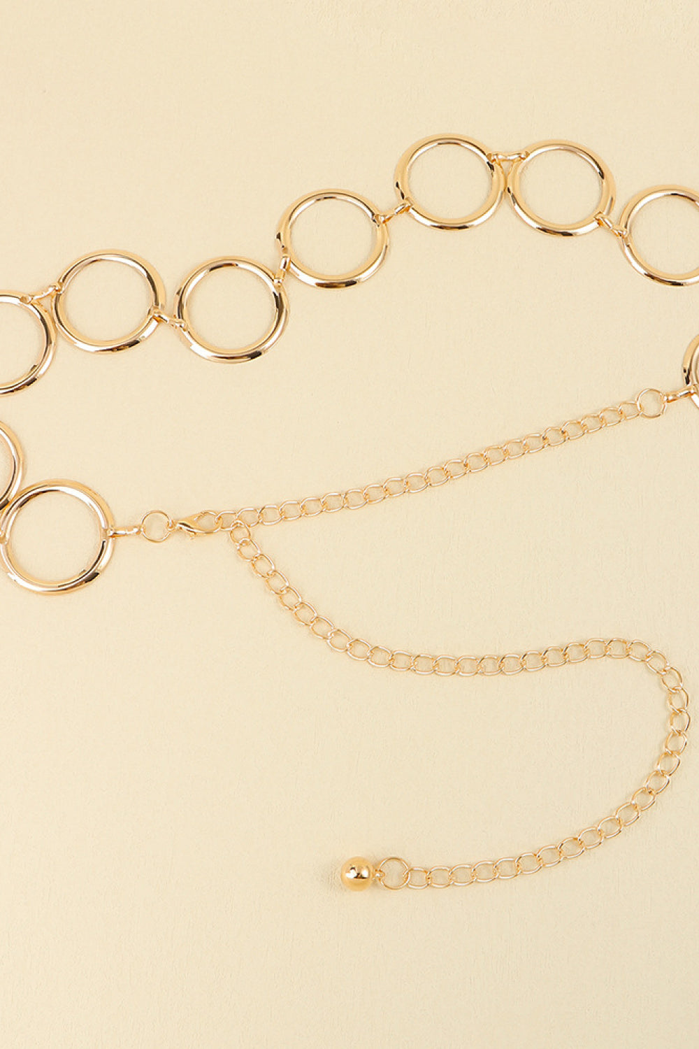 Gold geometric circle waist chain with delicate link chain and ball accent.