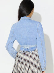 Medium wash denim wrap jacket with tie waist detail and asymmetric cut.