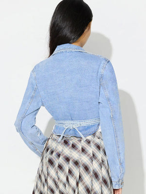Medium wash denim wrap jacket with tie waist detail and asymmetric cut.
