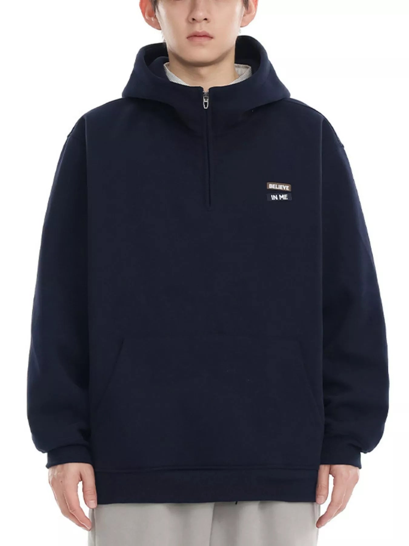 Navy blue quarter-zip hoodie with a small embroidered patch that says "BELIEVE IN ME".