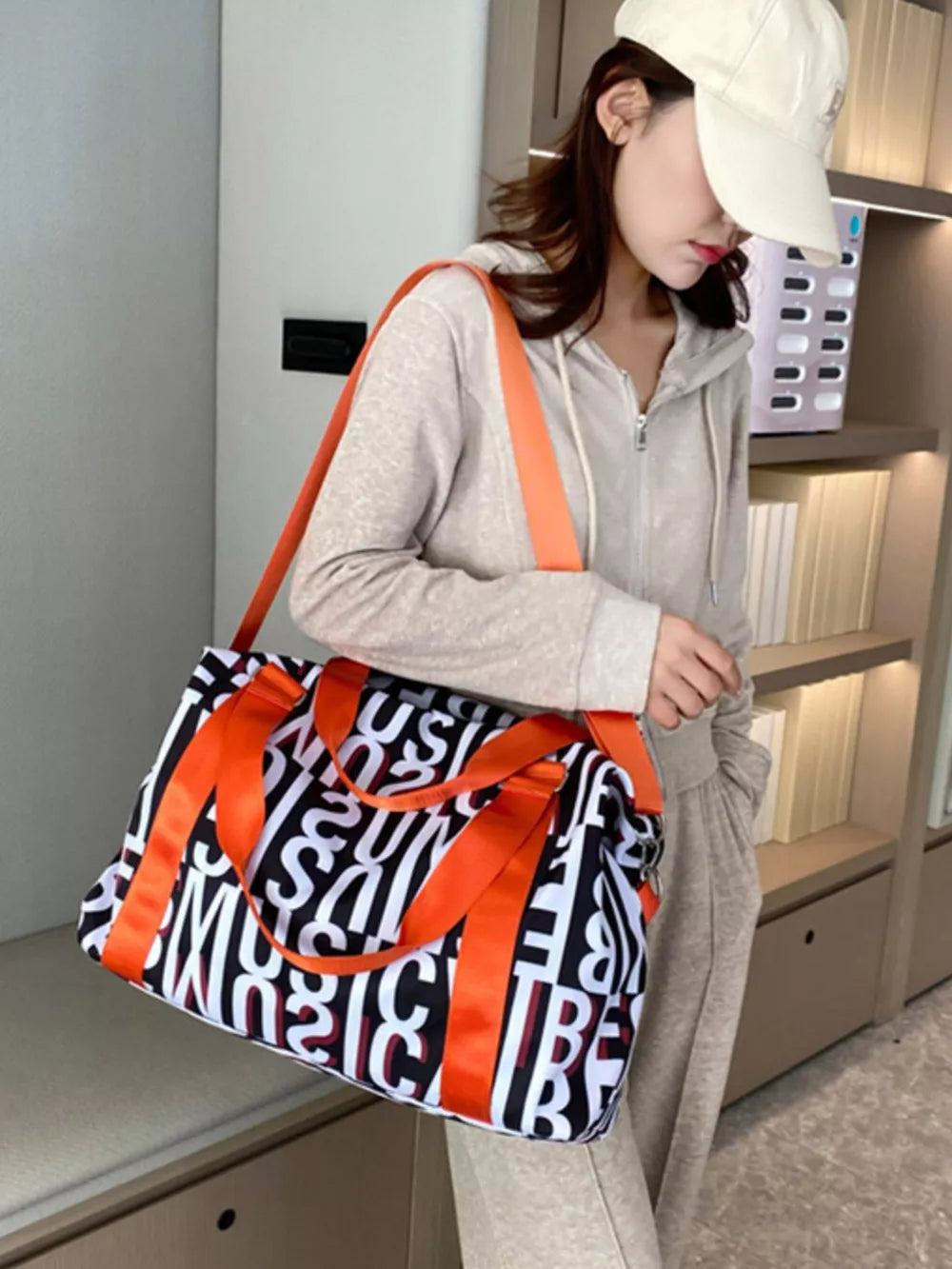 Chic letter print travel bag with orange straps and handles.