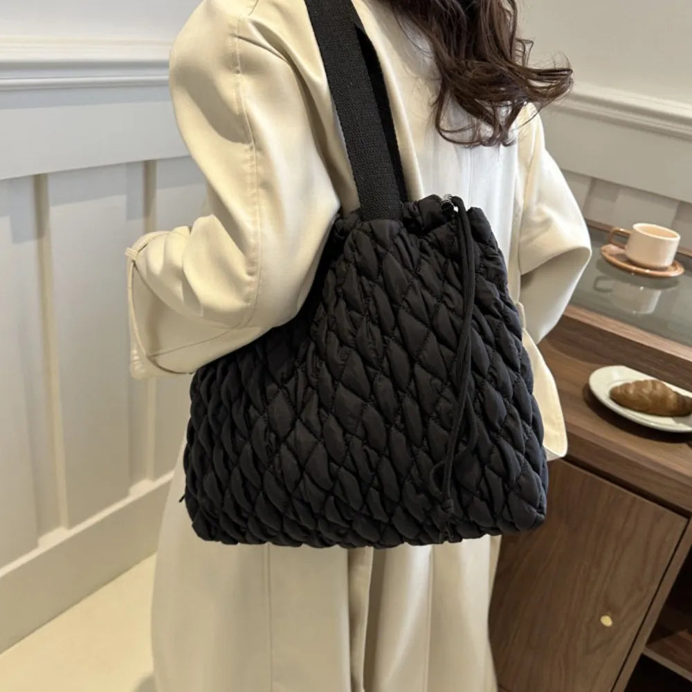 Black quilted drawstring carryall bag with diamond stitching and a single strap.
