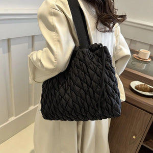 Black quilted drawstring carryall bag with diamond stitching and a single strap.