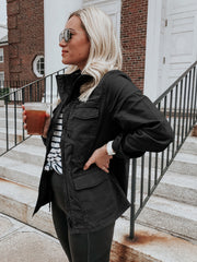 Black utility field jacket with multiple pockets and a stand-up collar.
