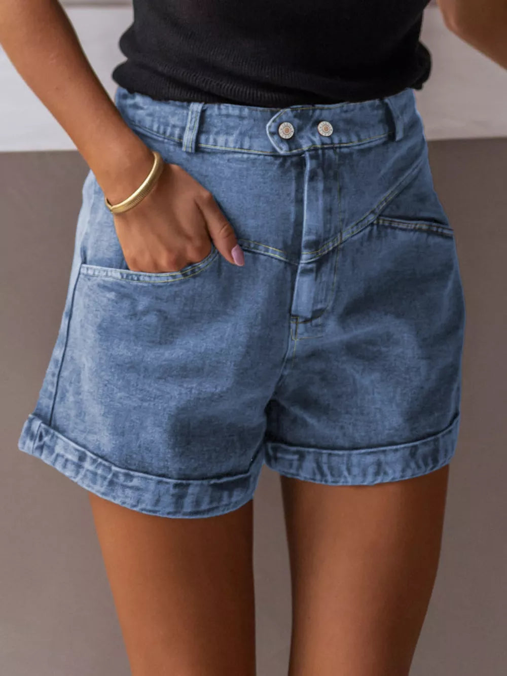Blue cuffed denim shorts with button fly and angular pockets.