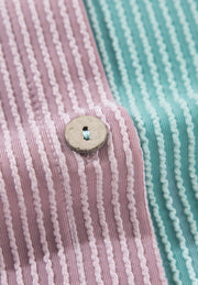 Waffle knit button-up shirt in dusty pink and teal colorblock with a wooden button detail.