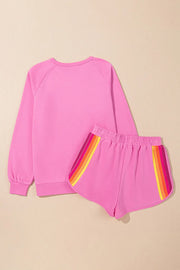 Fuchsia pink loungewear set with rainbow stripe detail on shorts and crewneck sweatshirt.