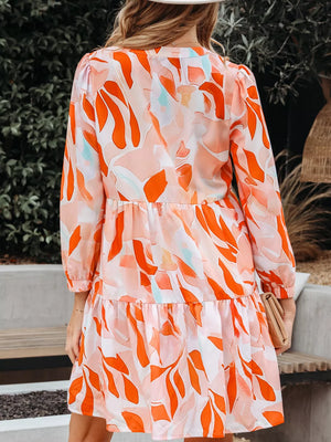 Tiered mini dress with vibrant abstract print, long sleeves, and a ruffled hem.