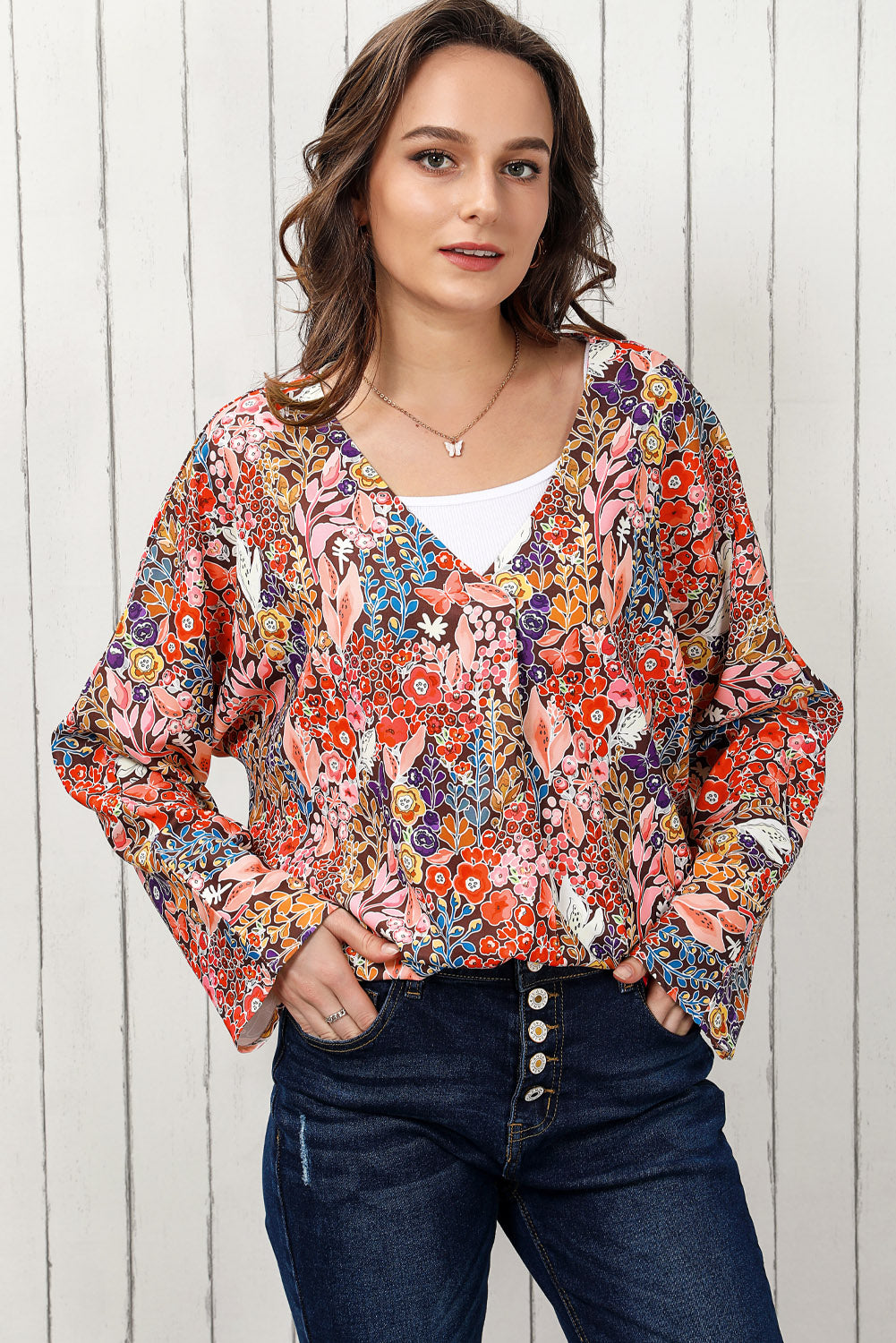 Painterly floral oversized blouse with V-neck and flared sleeves, worn with a white tank and jeans.