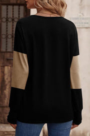 Black knit top with camel color block sleeves and button cuffs.