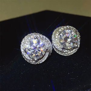 Halo diamond cluster stud earrings in silver with a central round-cut stone surrounded by smaller stones.