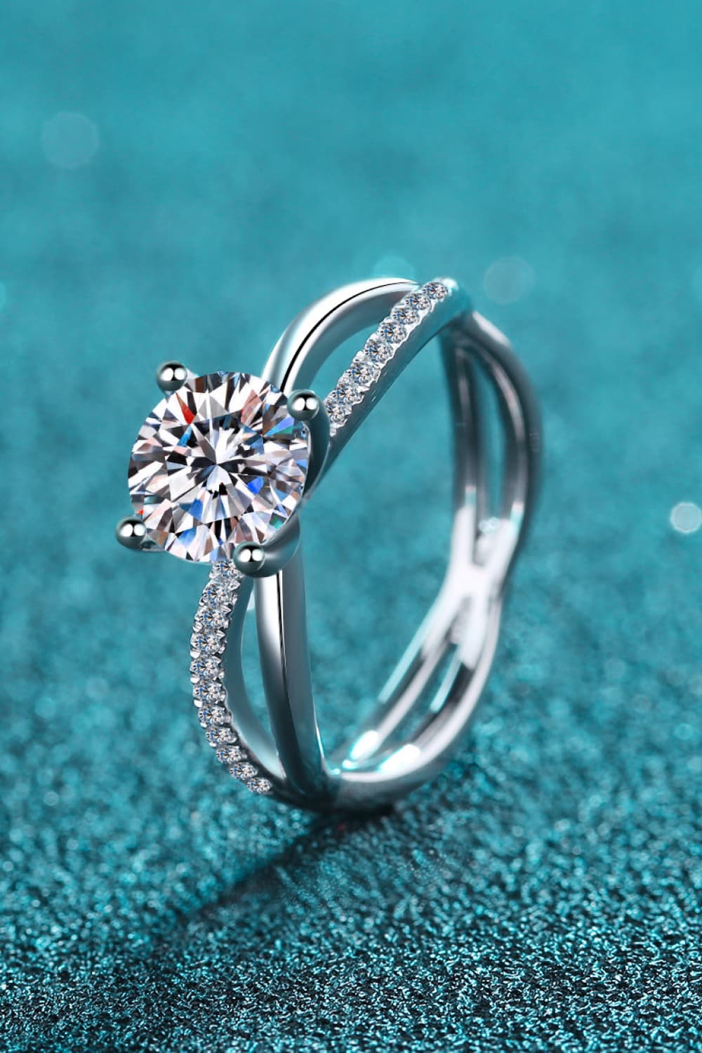 Silver crossover ring with solitaire moissanite and pavé band detail.