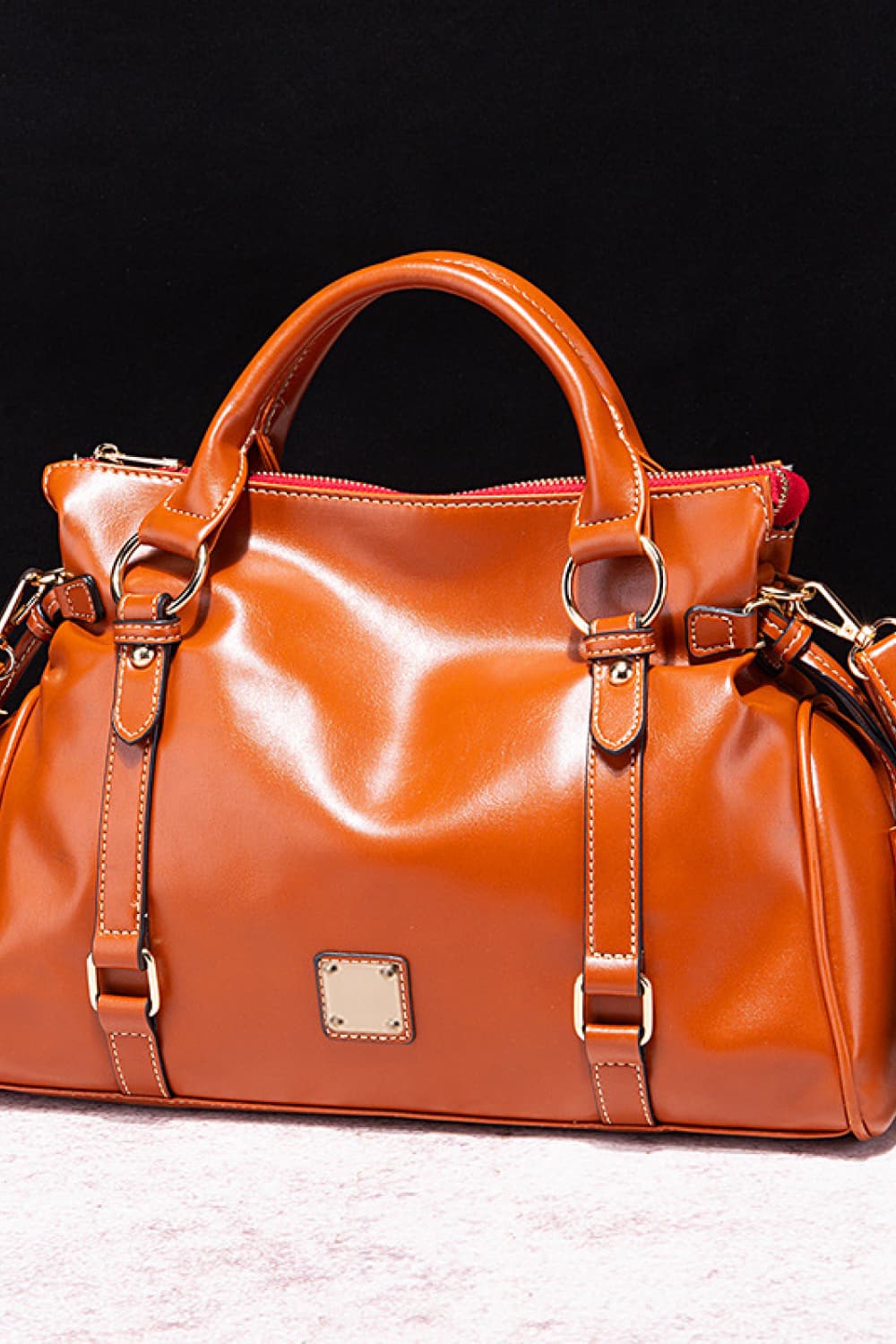 Caramel structured satchel bag with gold hardware and strap details.