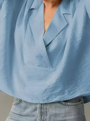 Light blue V-neck half sleeve shirt with a draped neckline, styled with jeans.