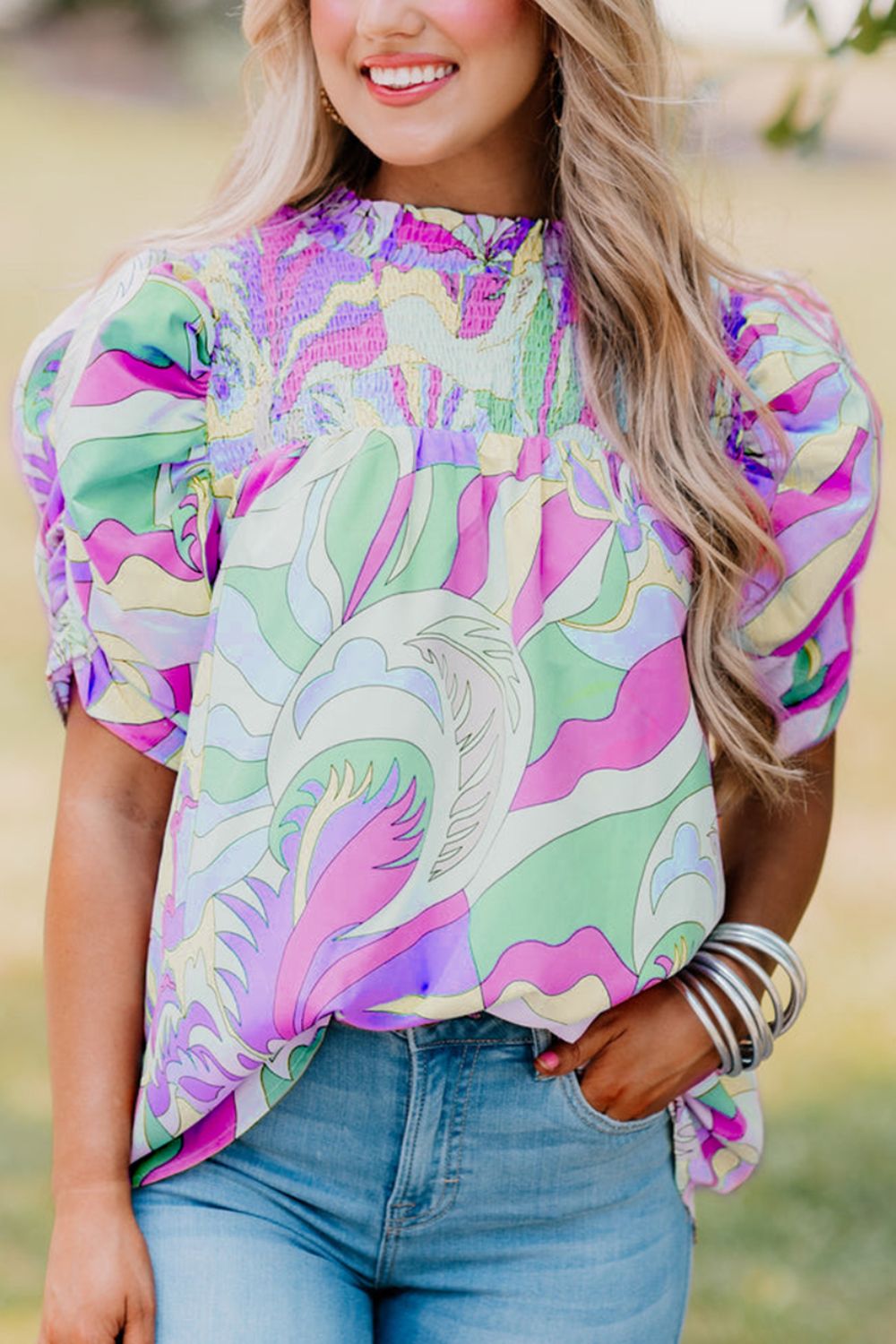 Multicolor smocked puff sleeve blouse with psychedelic print and gathered cuffs.
