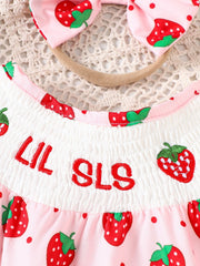 Baby one-piece in blush pink with strawberry print, smocked bodice, and embroidered text.