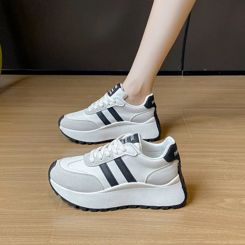 White platform trainers with black stripes and a chunky sole.