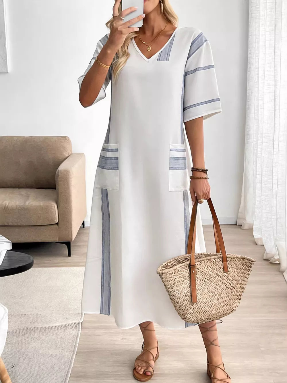 White maxi dress with blue stripes, V-neck, short sleeves, and pockets.