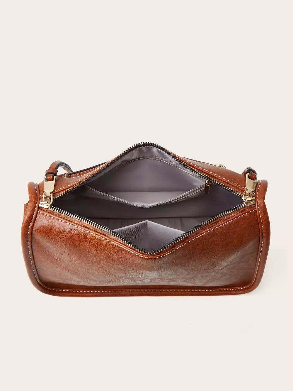 Tan leather crossbody bag with open interior and gold hardware.
