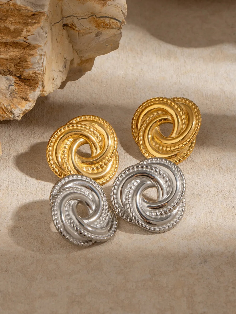 Golden swirl knot stud earrings in gold and silver finishes with textured edges.