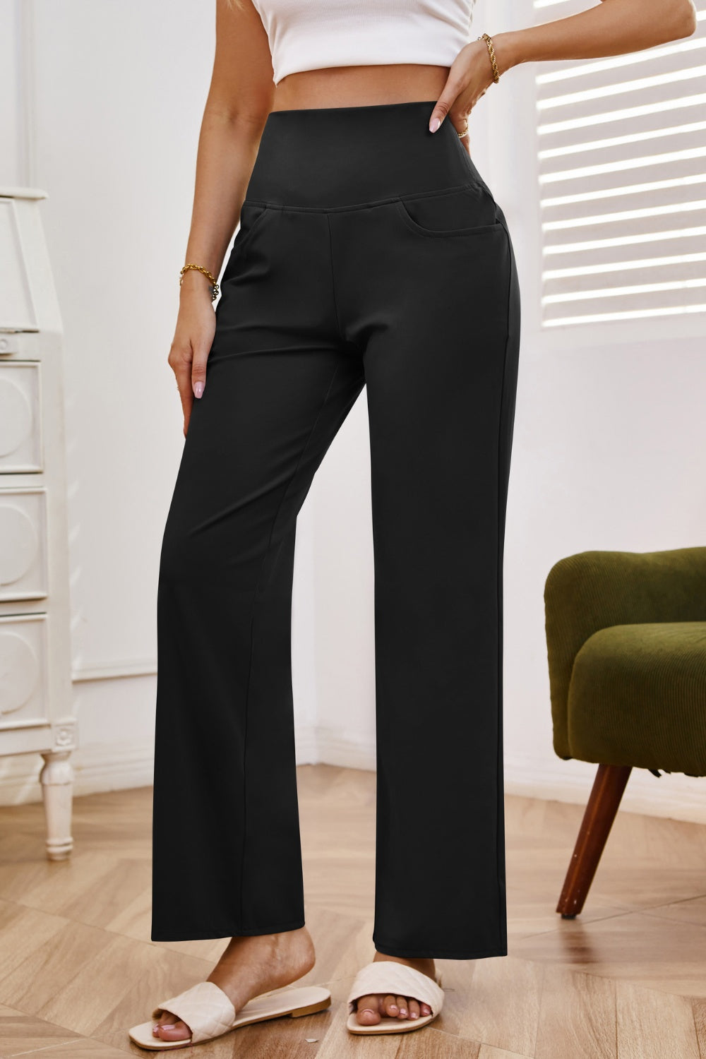 Black high-waisted flare leg trousers with pockets, styled casually.