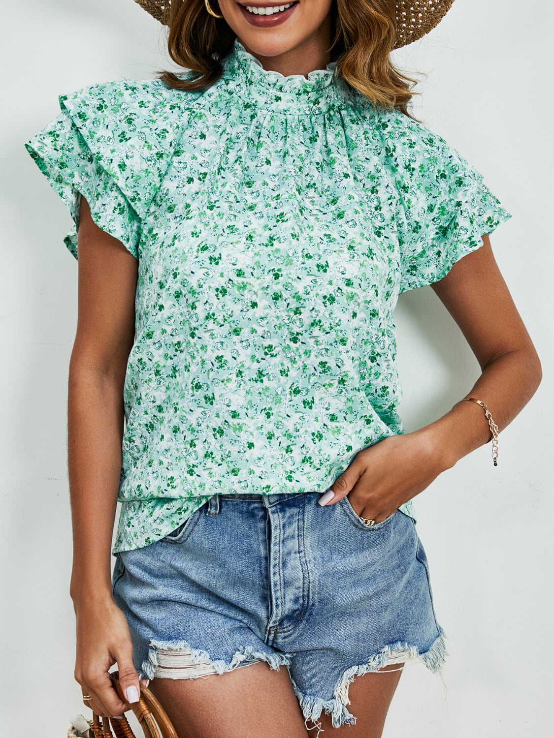 Light green floral blouse with ruffled neckline and flutter sleeves.