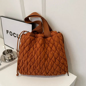 Quilted drawstring carryall handbag in terracotta with dual straps and diamond pattern.