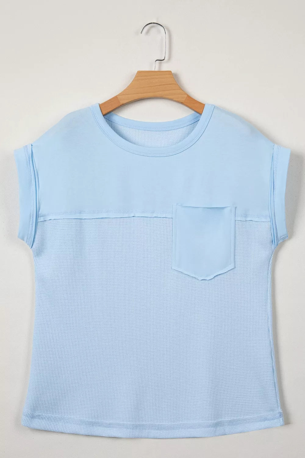 Light blue waffle knit t-shirt with short sleeves, crew neck, chest pocket, and curved hem.
