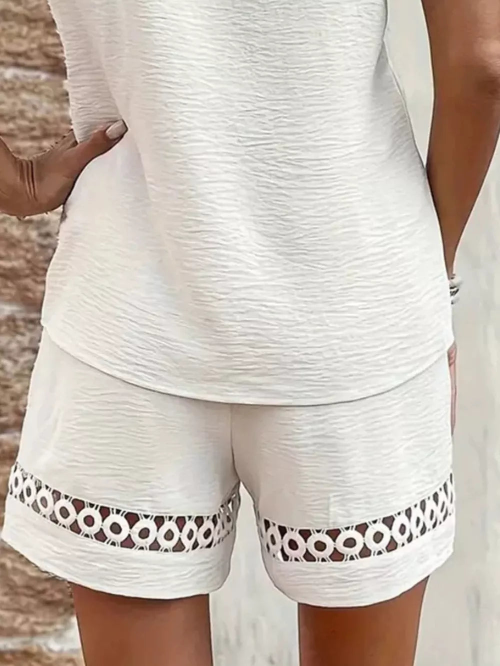 White lace-trimmed shorts with circular cutouts on the hem