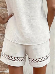 White lace-trimmed shorts with circular cutouts on the hem