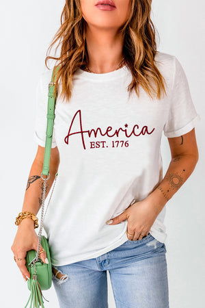 White t-shirt with "America EST. 1776" graphic in burgundy script.