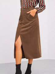 Brown corduroy midi skirt with high waist, button detail, pockets, and a thigh-high slit.