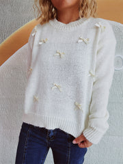 White knit crewneck sweater with scattered ribbon bows, crew neck, long sleeves.