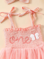 Pink smocked baby bodysuit with embroidered 'one' and butterfly detail, plus matching headband.