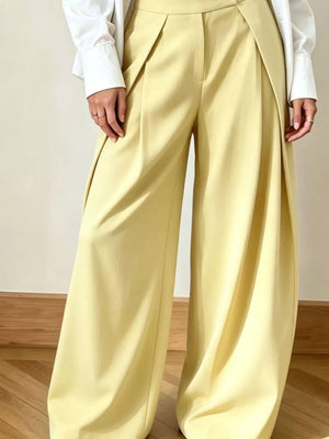Yellow wide-leg pants with a high waist and draped front detail, styled with a white shirt.